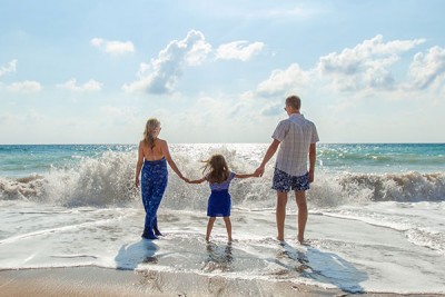 Family of 3 at the beach with ocean wave coming